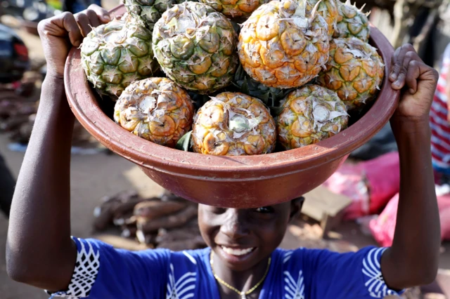 Un enfant porte un panier de fruits sur sa tête à Abidjan, Côte d'Ivoire - Mercredi 28 juillet 2021