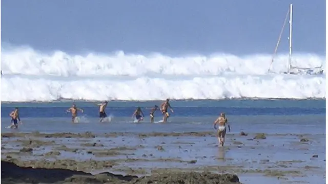 นักท่องเที่ยวกำลังวิ่งหนีคลื่นที่โถมเข้ามาเมื่อวันที่ 26 ธันวาคม 2547