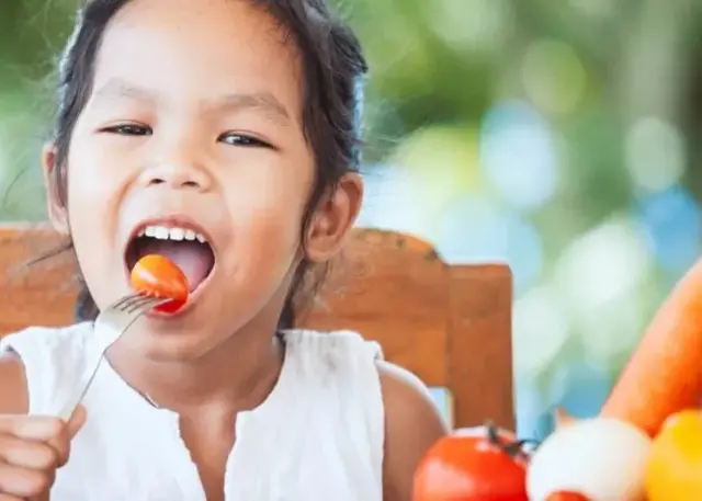 Un enfant mangeant une tomate