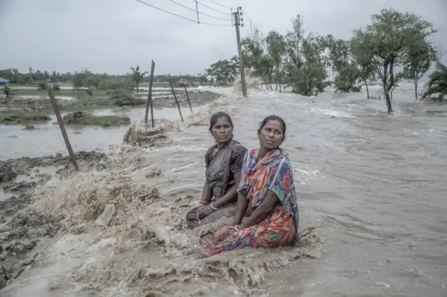 Dua wanita tak berdaya menyaksikan gelombang laut kembali merenggut rumah mereka di Sundarban, India