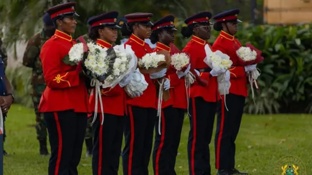 Soldiers hold flower bouquets to hand to officials 