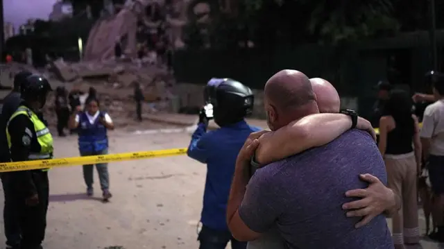 Dos hombres se abrazan frente a los escombros de un edificio que se derrumbó en el terremoto de 7,1 grados que azotó a Caracas el 24 de junio. 