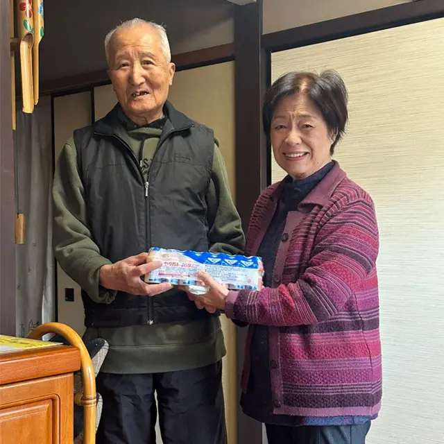 一对日本老年男女举起一排七瓶的养乐多（养乐多本社宣传图片）