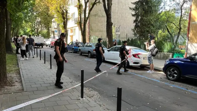 Полицейские оцепляют месо происшествия на улице.