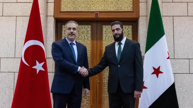 Hakan Fidan ve Eş Şara el sıkışırken. 