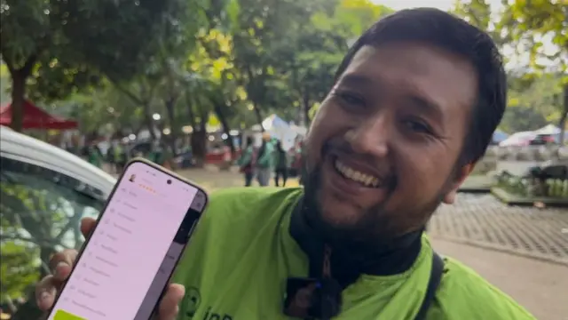 Seorang pengemudi ojol menujukkan aplikasinya.