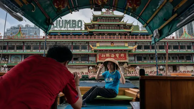 香港仔避風塘上一對男女搭乘舢板來到即將拖走的珍寶海鮮舫正門拍照留念(13/6/2022)