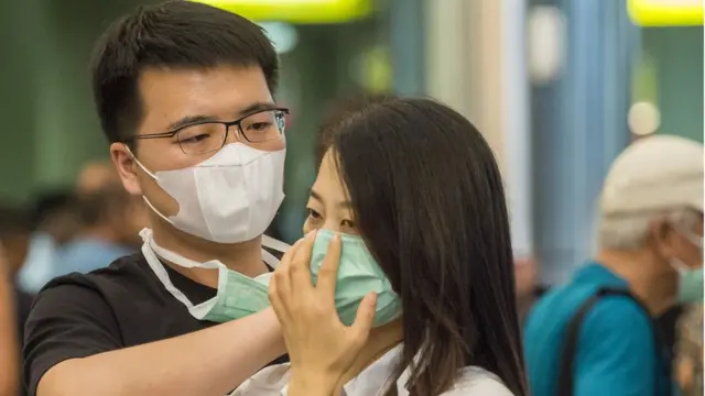 مواطن يساعد زميلته على ارتداء القناع