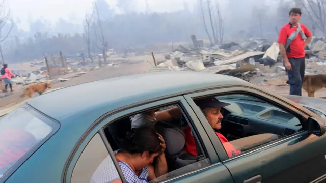 Gente en un coche en Santa Olga, completamente calcinado.