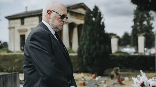 Hombre frente a una tumba.