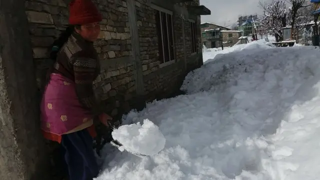 हिउँ तह लगाउँदै एक महिला