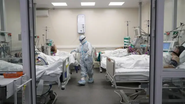 Pacientes con covid-19 en un hospital con un médico totalmente protegido.