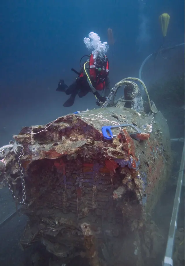 A French military diver member of the FS Pluton M622 navy de-mining ship, swims on July 2, 2018, above the wreck of an USAAF P-47 Thunderbolt (Warthog) US fighter plane