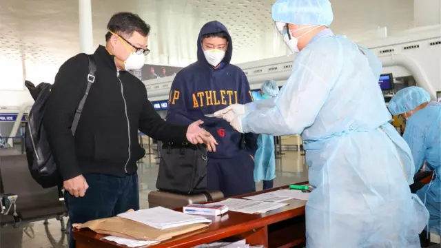 穿着保护装备的香港政府人员,在武汉天河国际机场为准备撤离的香港人登记。