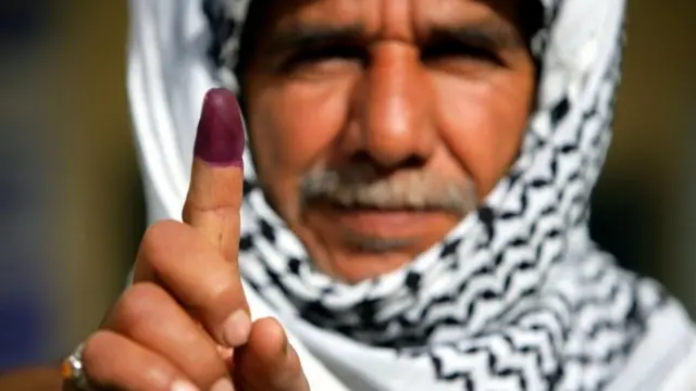 An Iraqi man holds up his ink stained finger after voting