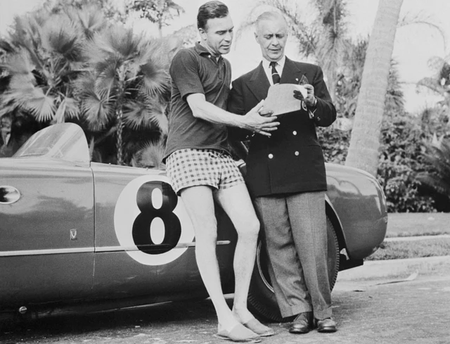 Porfirio Rubirosa junto a un auto de carrera.