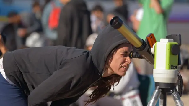 Una niña observa el eclipse con un telescopio