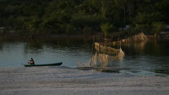 Homem rema em canoa no rio