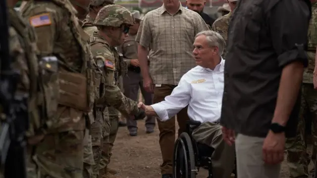 El gobernador de Texas, Greg Abbott, saludando a guardias armados en la frontera con México