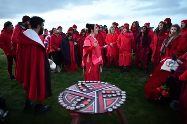 People sing during sunrise at Stonehenge in Wiltshire as crowds gather to mark the Winter Solstice,
