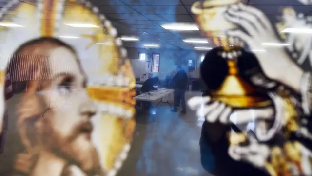 Un mural donde aparece Jesucristo y en el que se refleja un centro de votación estadounidense.