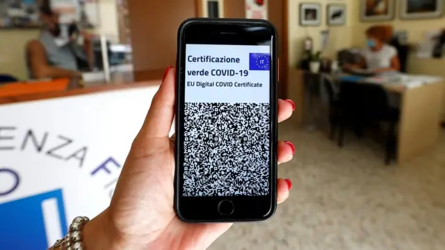 موظفة في مكتب في روما تبرز بطاقة "المرور الخضراء" الرقمية الخاصة بها