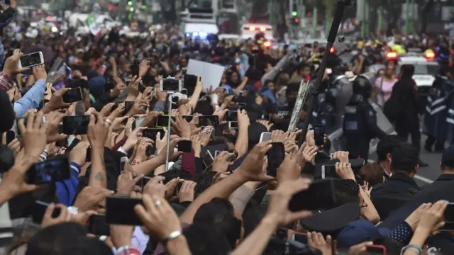Miles de personas con sus teléfonos móviles intentan captar el cortejo fúnebre.