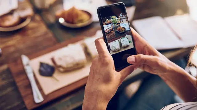 Cropped shot of a woman taking a picture on her phone of her food