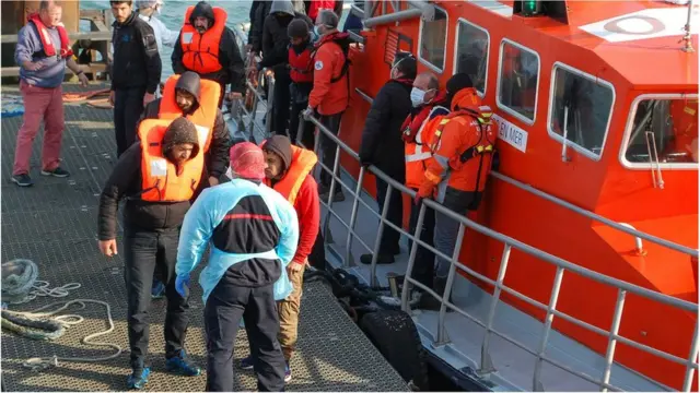 Des migrants descendent d'un bateau de secours après avoir été secourus le long de la côte française alors qu'ils tentaient de traverser la Manche vers le Royaume-Uni.