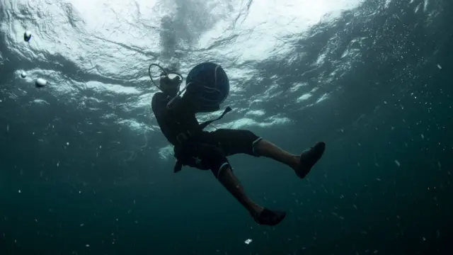 ภาพถ่ายใต้น้ำขณะชาวประมงพื้นบ้านดำน้ำลงไปวางไซ