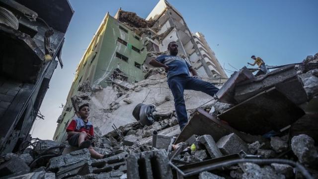 Palestinos inspecionam os escombros de sua casa destruída após ataques aéreos israelenses