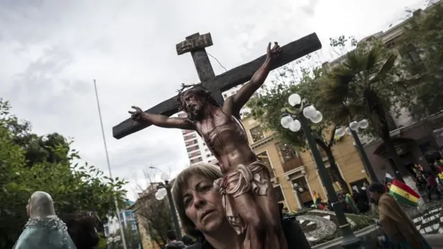 Mulher carrega um crucifixo durante protestos na Bolívia.