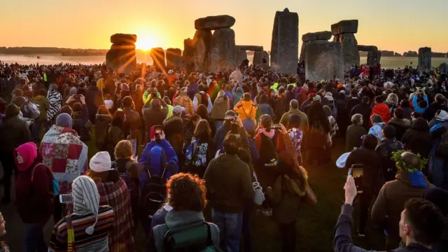 The sun rises between the stones and over crowds at Stonehenge where people gather to celebrate the dawn of the longest day in the UK. PRESS ASSOCIATION Photo. Picture date: Friday June 21, 2019.