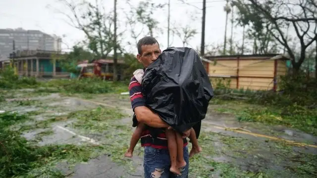 Pai carrega seus filhosbaixar o aplicativo do bets bolameio a forte chuva