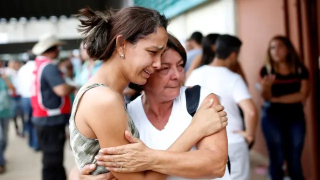 Mulheres se confortam em meio a busca por desaparecidos