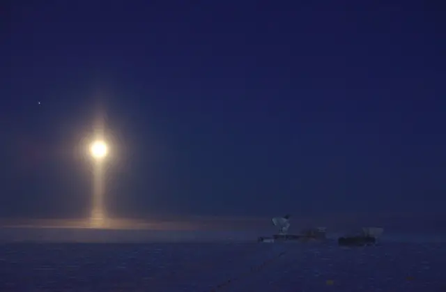 Місяць на темному небі зі стовпом світла під ним