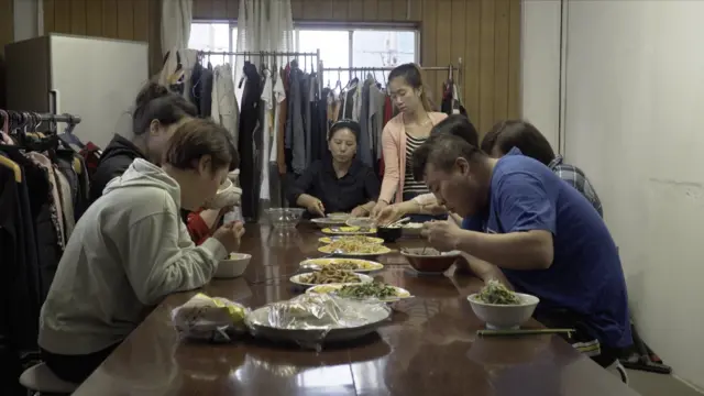 Buruh migran dari Asia di sebuah tempat penampungan di Jepang, duduk sambil makan malam bersama.
