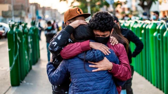 Familiares de pacientes de covid se abrazan frente a bombonas de oxígeno en Callao, Perú