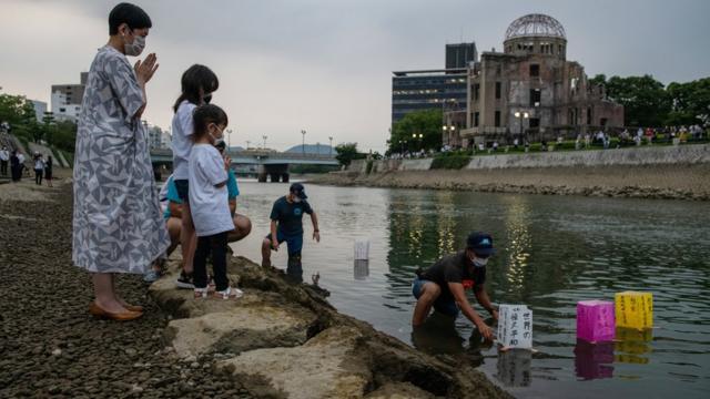 广岛原爆遗址对岸一家大小朝着给放到天满川上的祈福水灯合十（6/8/2020）
