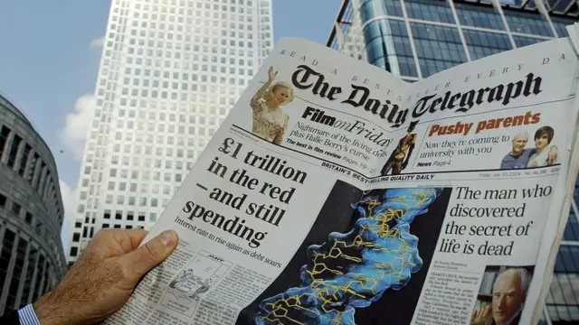 Mãos de um homem seguram uma edição do jornal Daily Telegraph