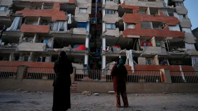 Dos personas frente a un edificio dañado