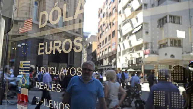 un hombre mira una vitrina con información sobre cambio de moneda