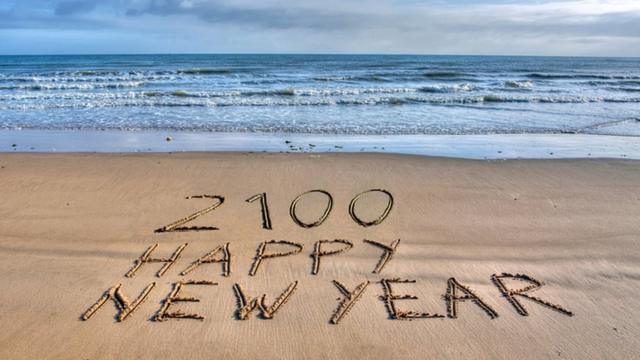 Feliz Año Nuevo 2100 escrito en la arena.