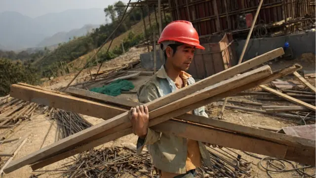 This picture taken on February 8, 2020 shows a Chinese worker carrying materials for the first rail line linking China to Laos, a key part of Beijing's 'Belt and Road' project across the Mekong, in Luang Prabang.