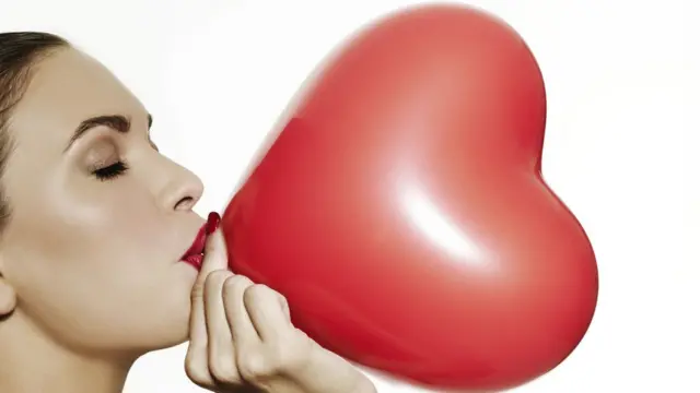 Mujer inflando globo de corazón