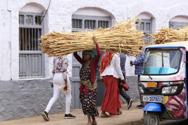 Mwanamke aliyebeba nyasi kavu akionekana kwenye mitaa ya Harar, Ethiopia - Jumamosi 19 Machi 2022