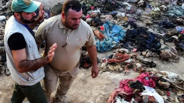 इराकी चिकित्सा परीक्षक पीड़ितों की सामूहिक कब्र की जगह पर खड़े हैं.