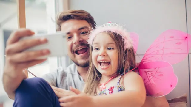 padre e hija usando celular