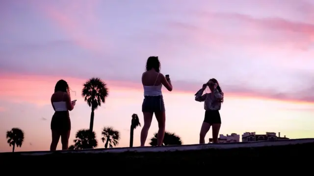 Jovens tirando fotos ao pôr do sol