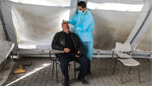 Врач берет мазок из носа к мужчины во время тестирования на коронавирус